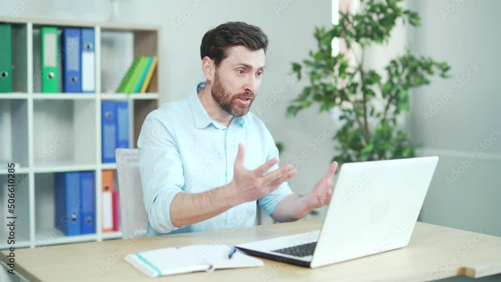 Angry enraged office worker shouting and arguing quarrels online talking on video call with colleagues or contractors. Communicates via webcam using laptop computer in office. Nervous male employee Angry enraged office worker shouting and arguing quarrels online talking on video call with colleagues or contractors. Communicates via webcam using laptop computer in office. Nervous male employee