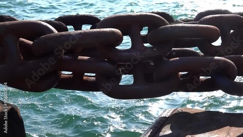Big iron chain of watercraft. Rusty chain tied to ship pier. POV. Actual camera, close up. Bollard with heavy chain. Strong relationship, solid bonds, reliability concept.