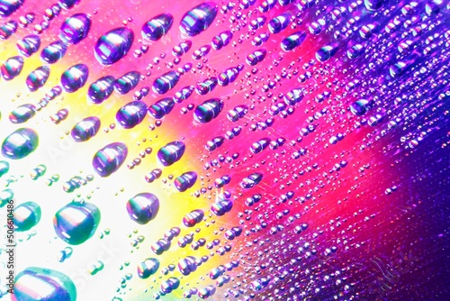 Colorful and vibrant water drops reflecting off of a Digital disc surface - rainbow-colored reflections and light play