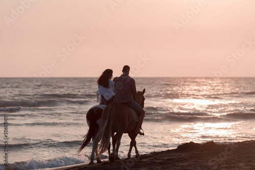 The family spends time with their children while riding horses together on a beautiful sandy beach on sunet.  © .shock