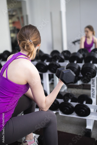 The girl is engaged in fitness in the gym. Playing sports in the gym. A set of exercises for the back. Women's health. Weight loss and a healthy body.