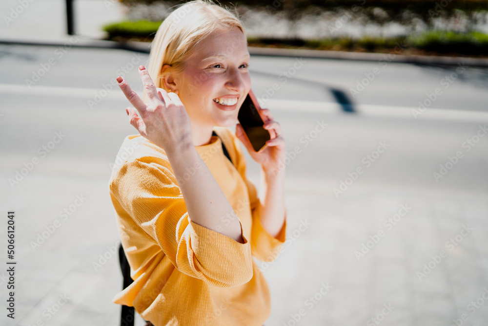 Happy girl walking on the street using the phone. Beautiful blonde girl talking to the smartphone Happy girl walking on the street using the phone. Beautiful blonde girl talking to the smartphone