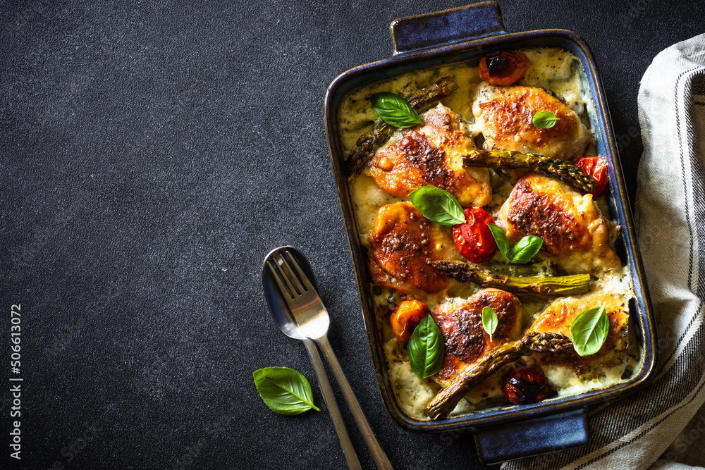 Baked chicken thighs with asparagus and vegetables in a creamy sauce.