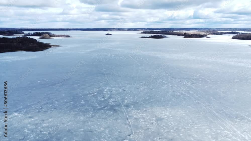 Flight on the drone over large forest lake covered with ice. Lake with small islands. Flight on the drone over large forest lake covered with ice. Lake with small islands.