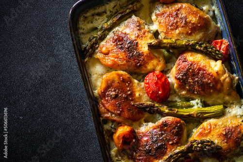 Baked chicken thighs with asparagus and vegetables in a creamy sauce.