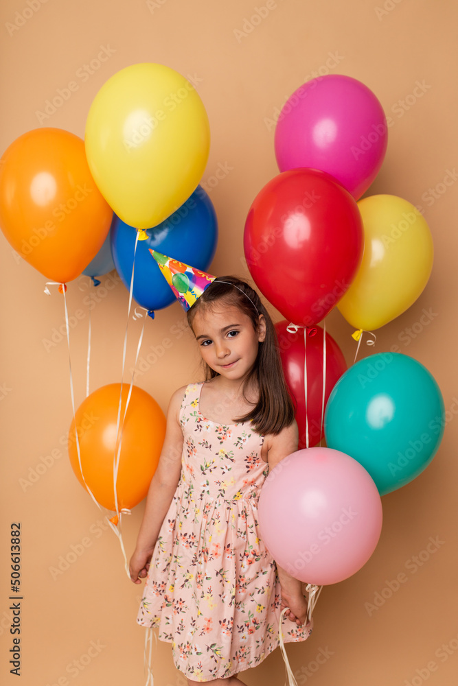 Obraz premium Happy Birthday party. Child girl with balloons on beige background