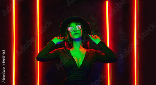 Portrait of a beautiful fashionable woman in classic hat surrounded by colorful neon light.