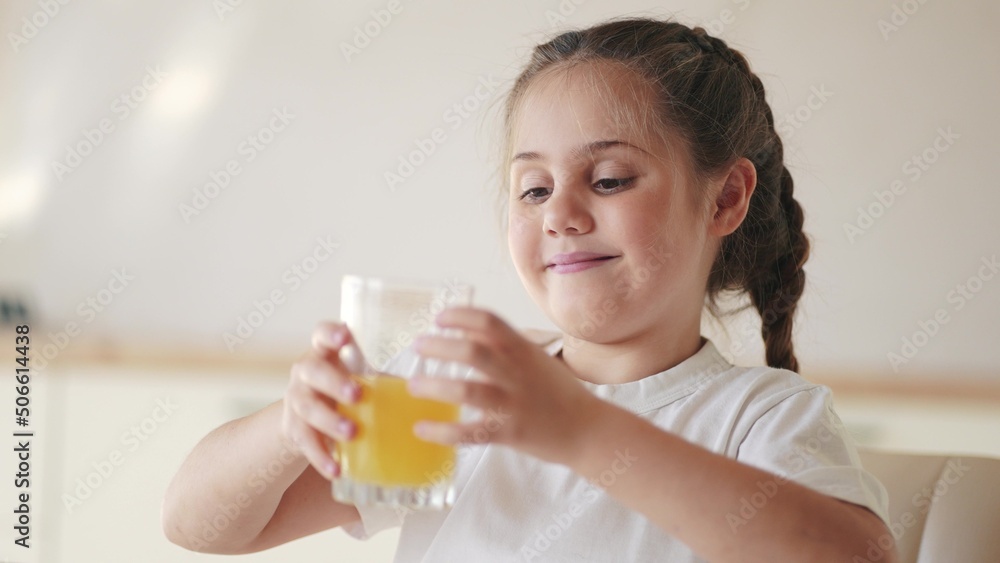 girl child drinking juice. happy family a healthy eating kid dream concept. indoors daughter girl drinking yellow juice from a glass cup in the kitchen. child drinking fruit juice girl child drinking juice. happy family a healthy eating kid dream concept. indoors daughter girl drinking yellow juice from a glass cup in the kitchen. child drinking fruit juice