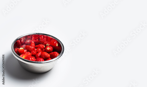 Stainless bowl with strawberries on white background with copy space.