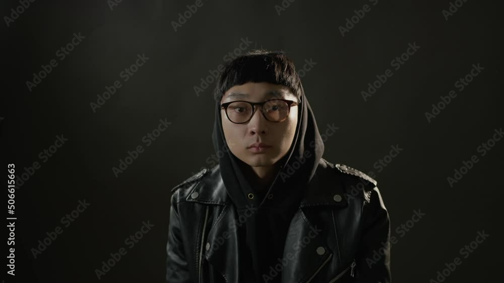 A man puts in glasses and a hood turn around itself. Shot from the film. Man looks at the camera against a dark background. A man puts in glasses and a hood turn around itself. Shot from the film. Man looks at the camera against a dark background.