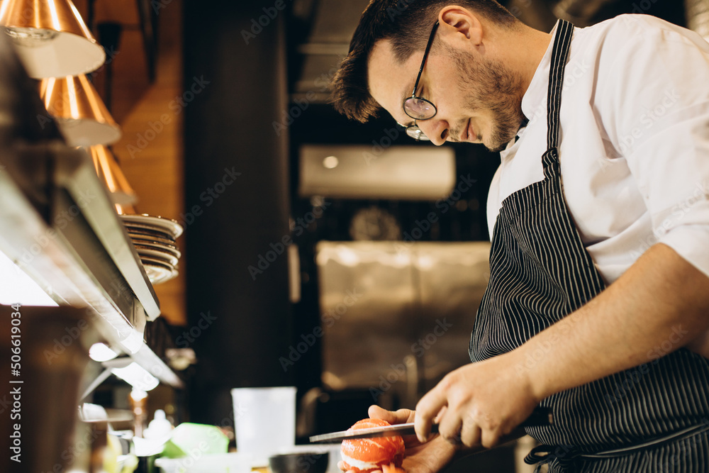 Man chef cutting grapefruit at the kitchen restaurant
