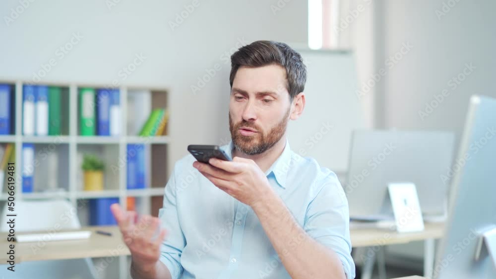 Confident mature bearded business man, employee talking on speaker phone working at computer desk at workplace in modern office. Successful Handsome male worker communicates and speaks sitting indoor Confident mature bearded business man, employee talking on speaker phone working at computer desk at workplace in modern office. Successful Handsome male worker communicates and speaks sitting indoor