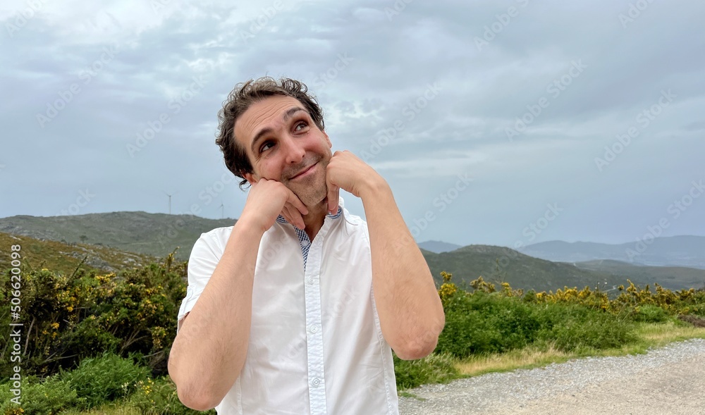 man with funny face He brought his hands to his face and smiled against the backdrop of the mountains. High quality photo man with funny face He brought his hands to his face and smiled against the backdrop of the mountains. High quality photo