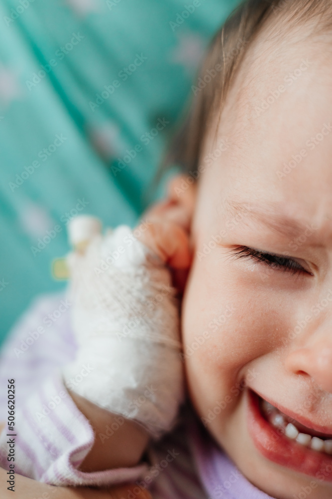 a child with a catheter in his hand cries a lot and cries while lying in bed in the hospital a child with a catheter in his hand cries a lot and cries while lying in bed in the hospital