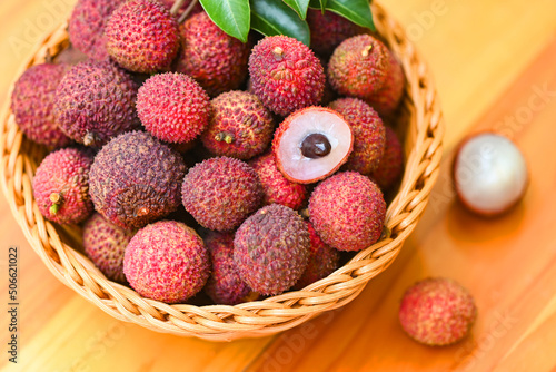 Lychee fruit on basket with green leaf and wooden background, fresh ripe lychee peeled from lychee tree at tropical fruit Thailand in summer