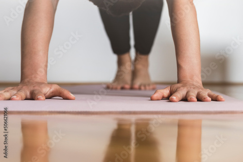 Female stands in plank doing fitness on the exercise mat focus on hands.