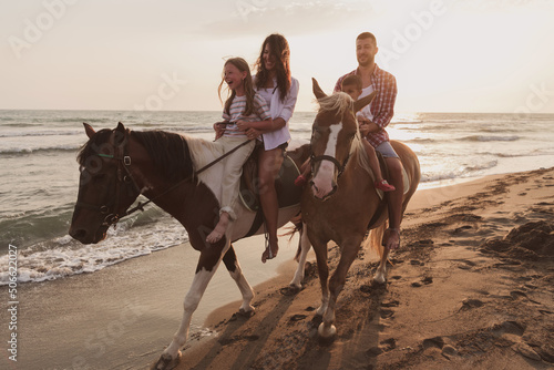 The family spends time with their children while riding horses together on a sandy beach. Selective focus  © .shock