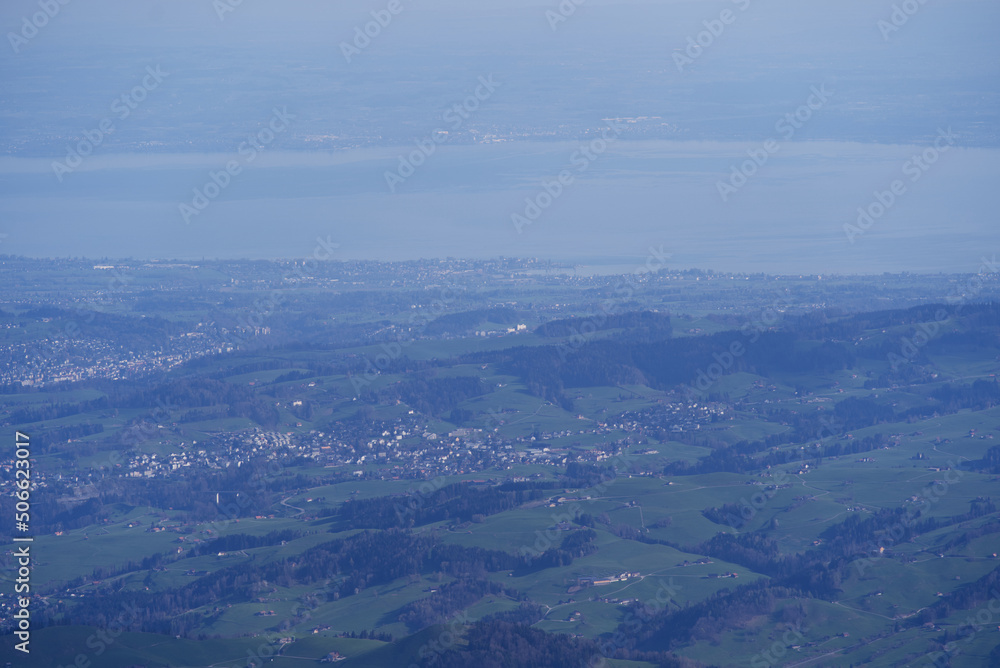 Aerial view with Mountains and midland and lake Bodensee in the background seen from Säntis peak at Alpstein Mountains on a sunny spring day. Photo taken April 19th, 2022, Säntis, Switzerland.