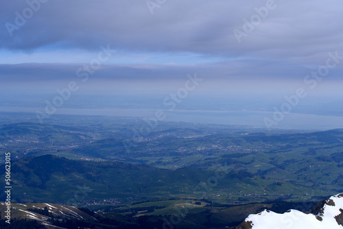 Aerial view with Mountains and midland and lake Bodensee in the background seen from Säntis peak at Alpstein Mountains on a sunny spring day. Photo taken April 19th, 2022, Säntis, Switzerland. © Michael Derrer Fuchs