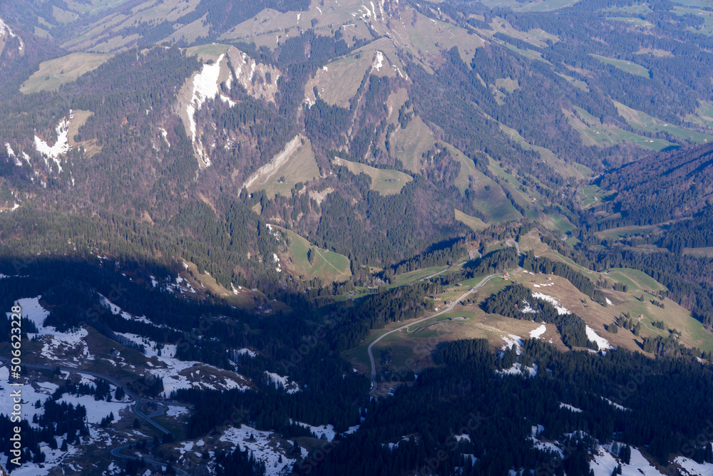 Aerial view with Mountains and woodland seen from Säntis peak at Alpstein Mountains on a sunny spring day. Photo taken April 19th, 2022, Säntis, Switzerland.
