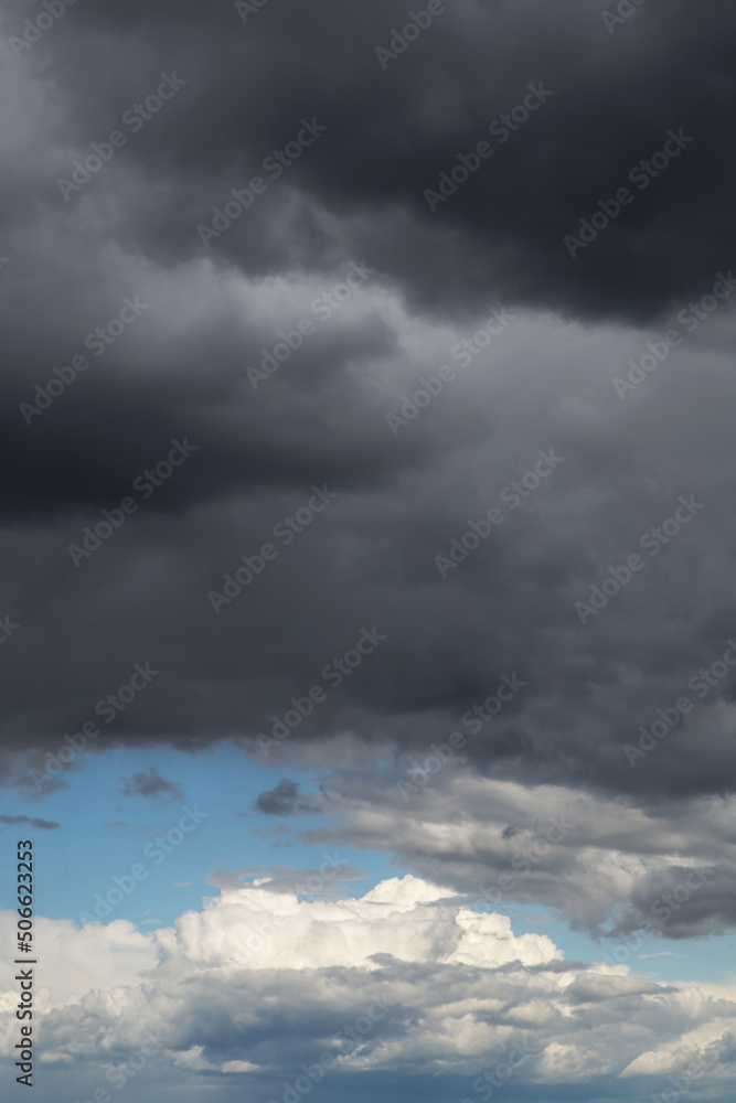 Epic Dramatic storm dark grey and white cumulus rain clouds against blue sky background texture, thunderstorm	