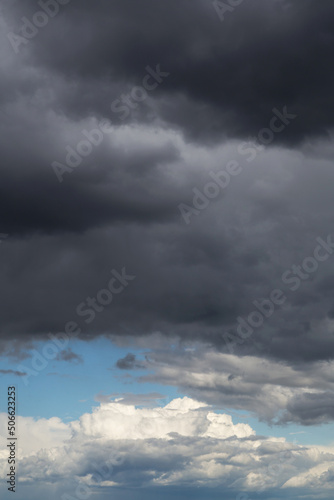 Epic Dramatic storm dark grey and white cumulus rain clouds against blue sky background texture, thunderstorm 