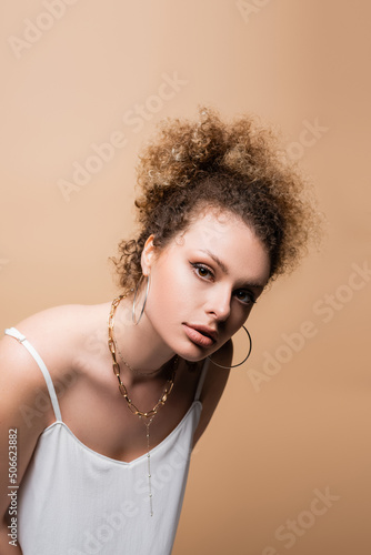Young woman in white top and accessories isolated on beige.