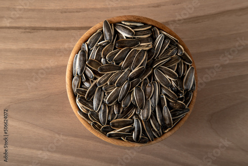 Black sunflower seeds in a bowl on wooden background photo