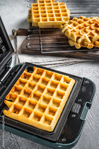 Cooking of fresh waffles in waffle maker. White background. Top view