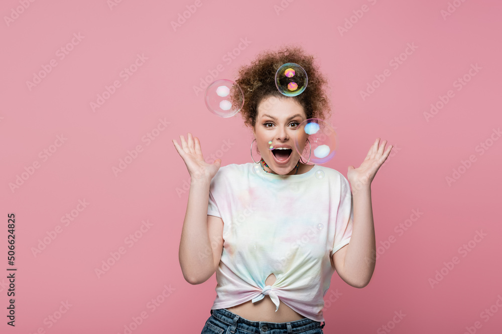 Shocked young woman standing near soap bubbles on pink background. Shocked young woman standing near soap bubbles on pink background.