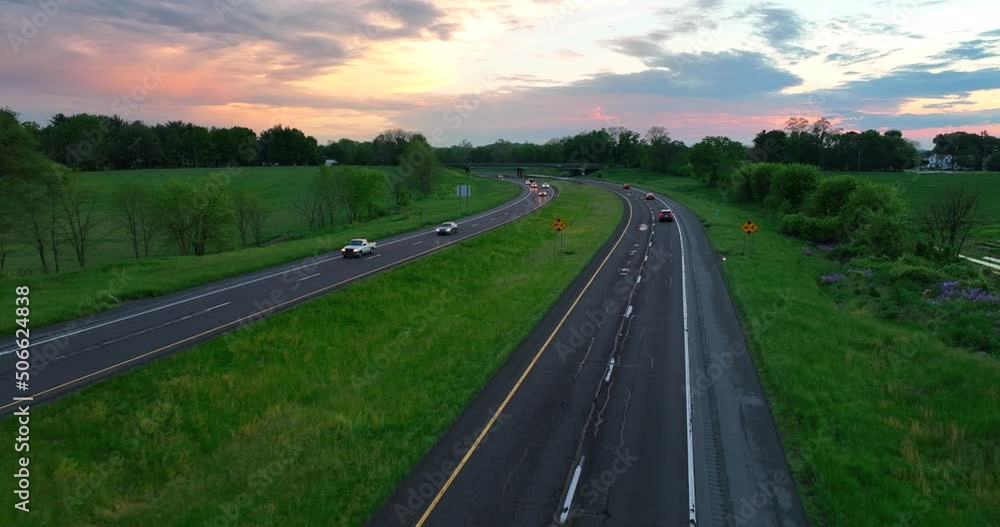 Aerial flyover of highway in rural USA. Drone shot of cars on road after storm. Beautiful color in sky from sunset. Aerial flyover of highway in rural USA. Drone shot of cars on road after storm. Beautiful color in sky from sunset.