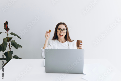 Woman with bitcoin sitting at the table on grey background