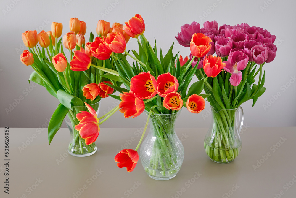 Different beautiful flowers in vases on table against light background. Spring holiday concept. Selective focus