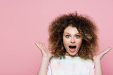 Shocked curly woman looking at camera isolated on pink.