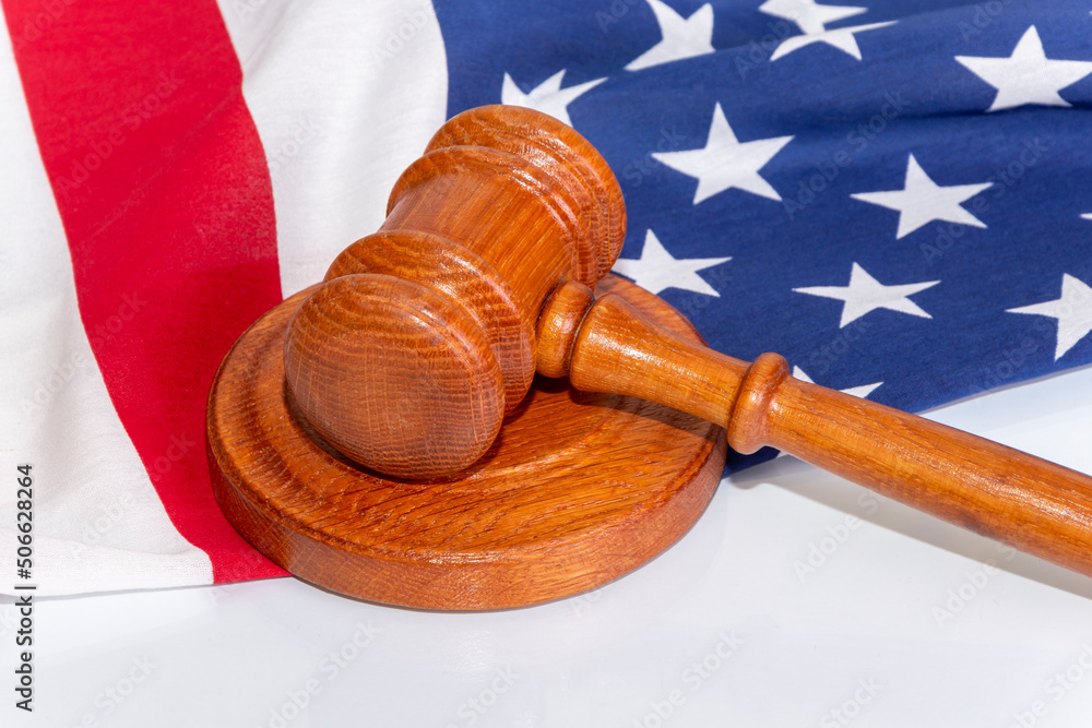 Wooden judge's gavel on the background of the American flag. Concept: claim and compensation for damages, court session, announcement of the verdict, trial.
