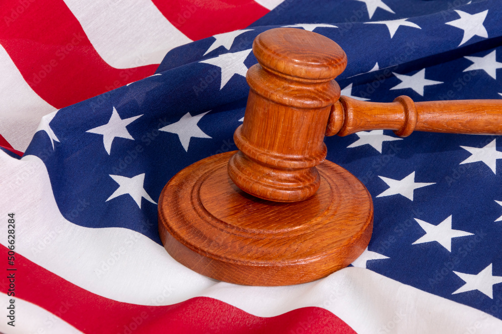 Wooden judge's gavel on the background of the American flag. Concept: claim and compensation for damages, court session, announcement of the verdict, trial.