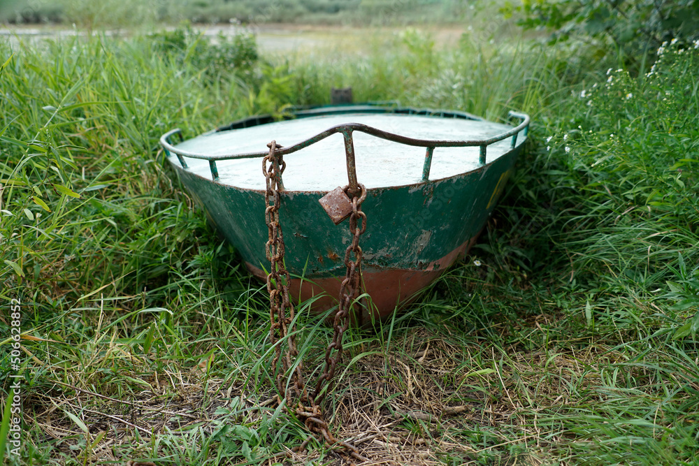 A boat out of the water on the grass, with a chain and padlock A boat out of the water on the grass, with a chain and padlock
