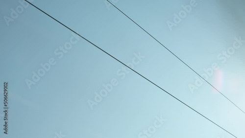 Moving catenary wire of the railway in europe with blue sky and trees moving past in the background. photo