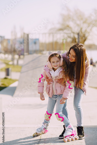 Mother with daughter in a spring park with roller