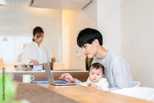 赤ちゃんと一緒にパソコンを使うパパ