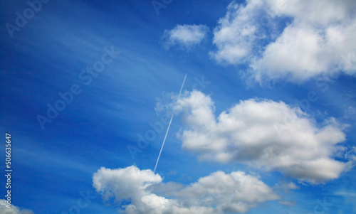 A twin-engine jet aircraft with a reverse wake against a blue sky with white clouds. photo