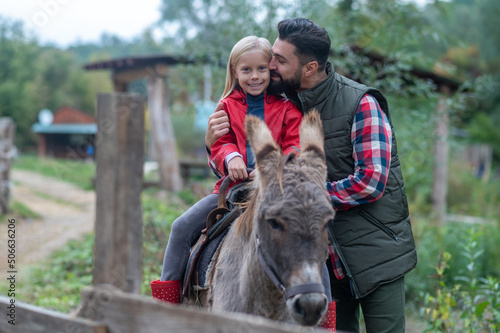 Father and daughter at the cattle-farm with a donkey
