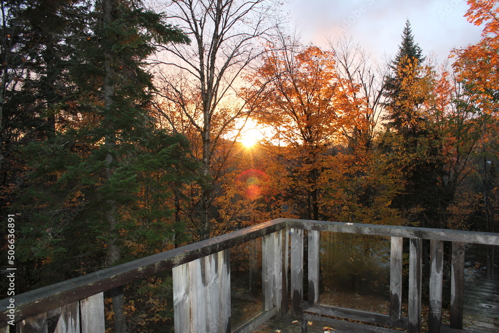 Sunset over a forest in the mountains in the middle of autumn from the wooden balcony of the chalet