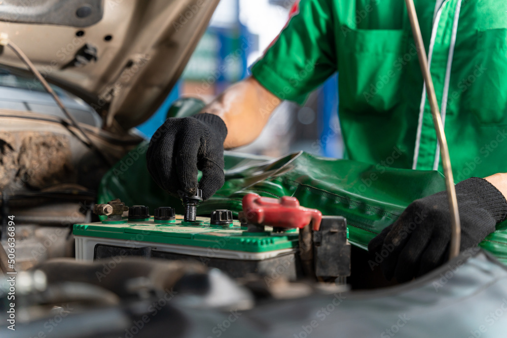 Auto mechanic checking battery for the customers who come to use the battery replacement service at the shop. Auto mechanic checking battery for the customers who come to use the battery replacement service at the shop.