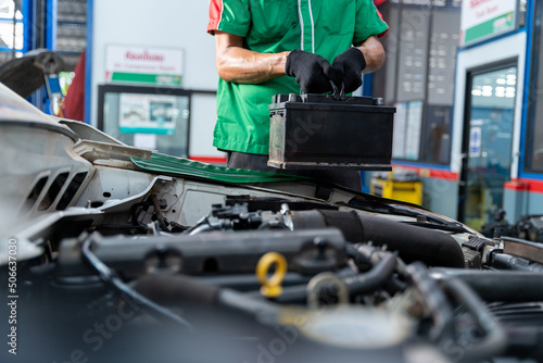 Auto mechanic is about to repair battery for the customers who come to use the battery replacement service at the shop.