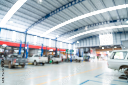 Blurred of Auto mechanic working in Car repair station paved with epoxy floor and electric lift for a car that comes to change the engine oil in the background of Car repair center with epoxy floors. © tong2530