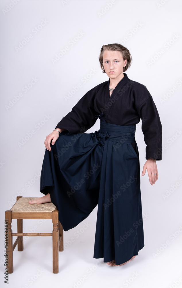 junger mann in traditionellem Kendo Gewand, einen Fuß auf Stuhl gestellt