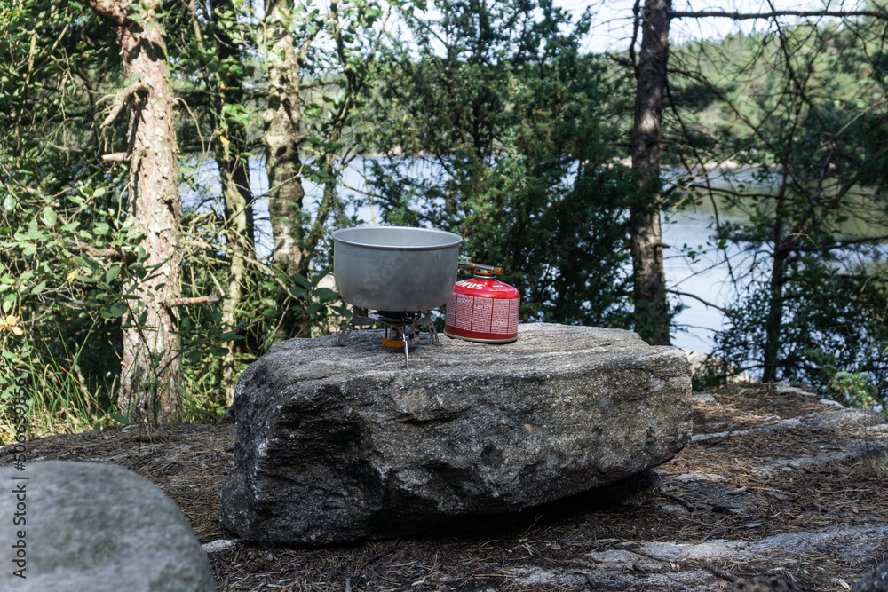 Campingkocher und Metalltopf auf einem Felsen an einem see