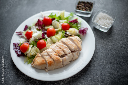 plate with chicken fillet and salad with vegetables on a stone background