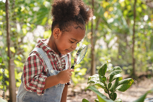 Happy kid girl use magnifying glass to tree pot at agriculture farm	